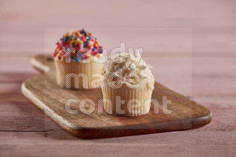Vanilla mini cupcake topped with coconut on a wooden board