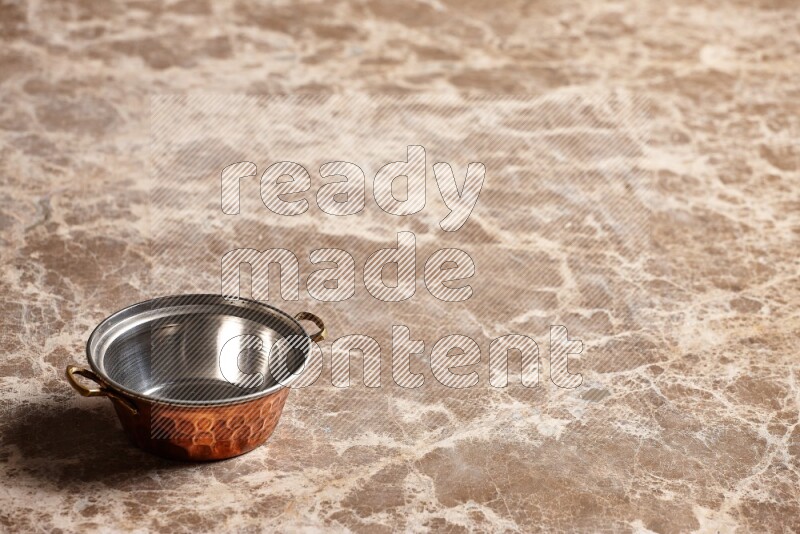 A small copper pot on beige marble background