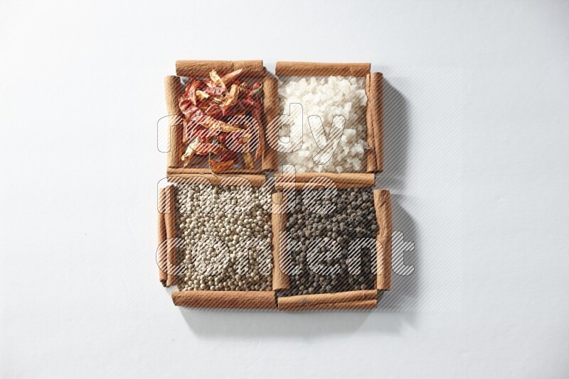 4 squares of cinnamon sticks full of red chilis, salt, white pepper, and black pepper on white flooring