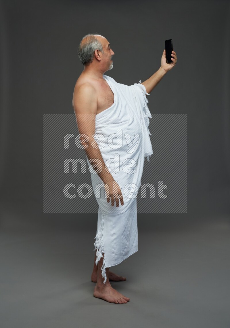 A man wearing Ehram Standing taking selfie on gray background