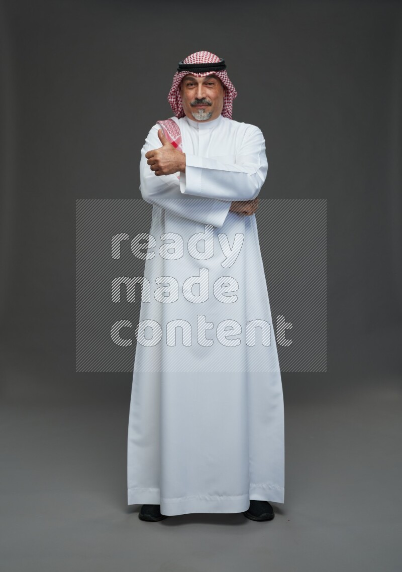 Saudi man with shomag Standing Interacting with the camera on gray background