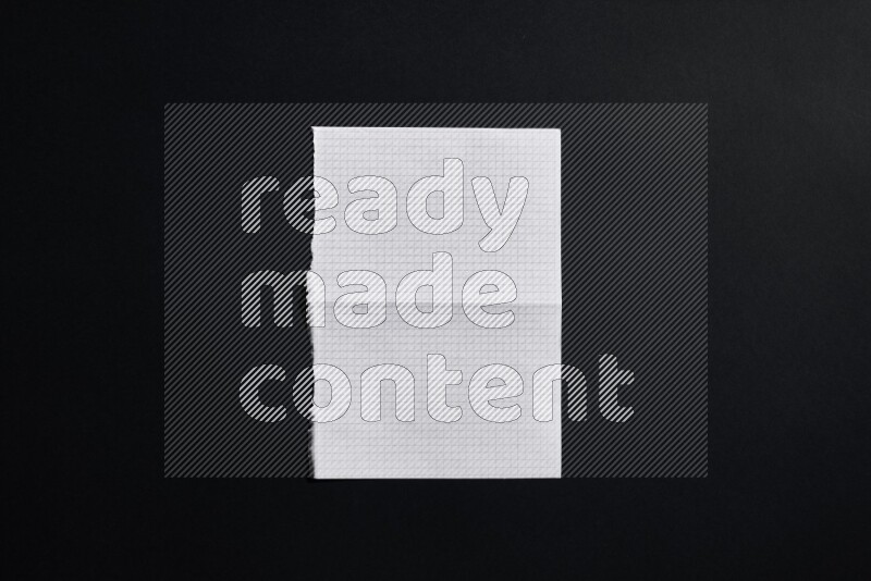 Folded notebook sheet on black background