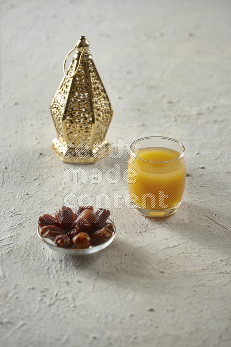 A golden lantern with different drinks, dates, nuts, prayer beads and quran on textured white background