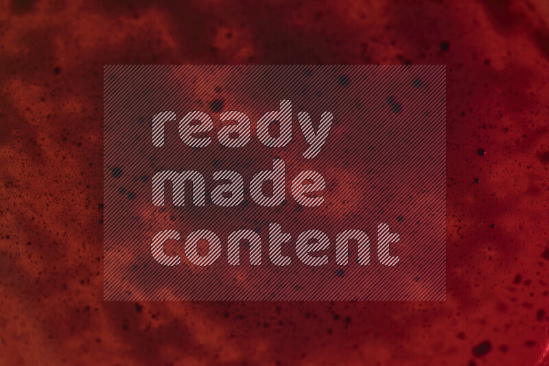 Close-ups of abstract blue watercolor drops on oil Surface on red background