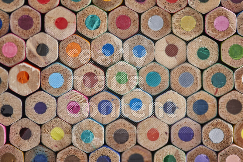 A close-up of the tips of colored pencils arranged in a bundle on white background