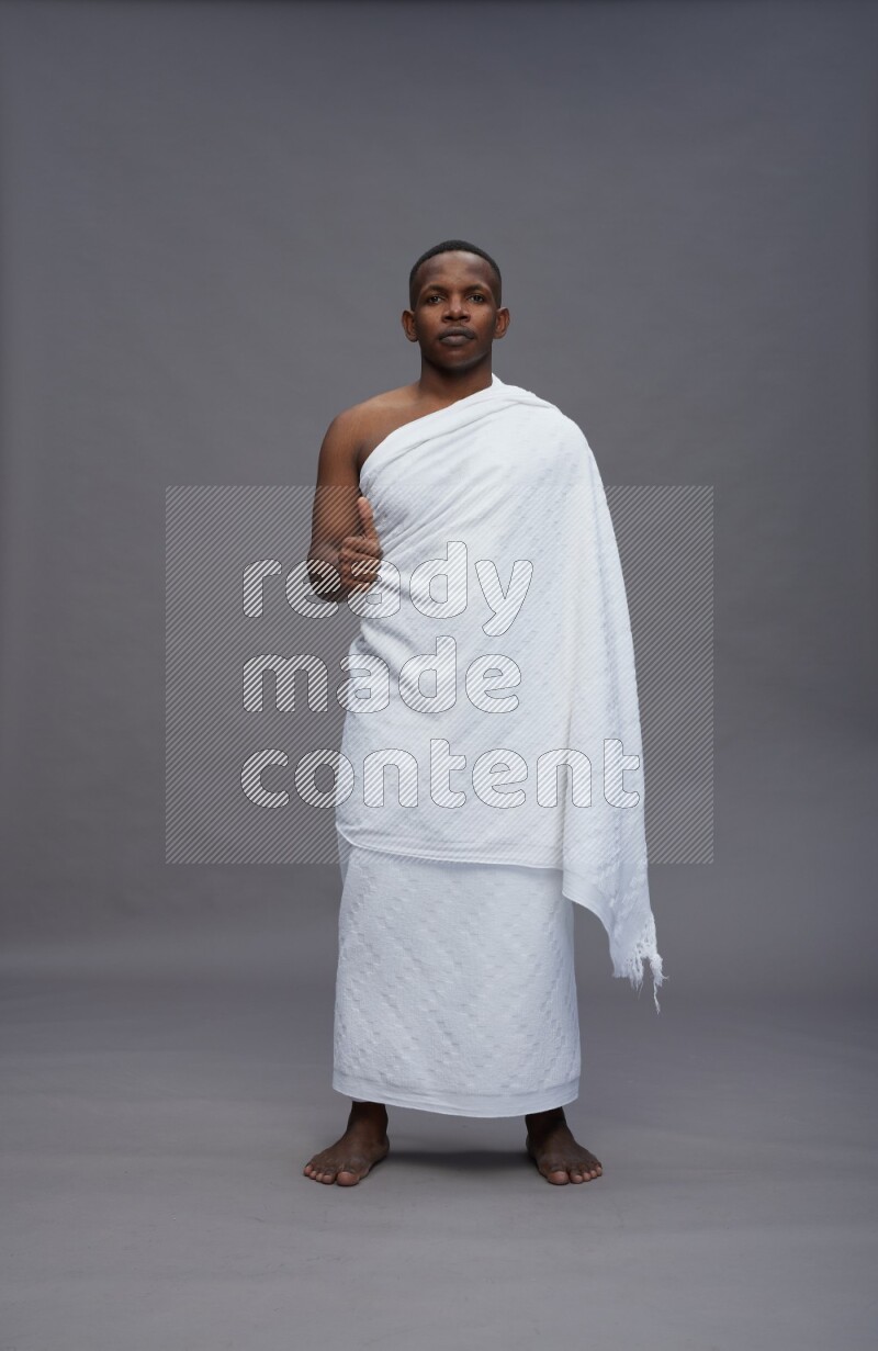 A man wearing Ehram Standing Interacting with the camera on gray background
