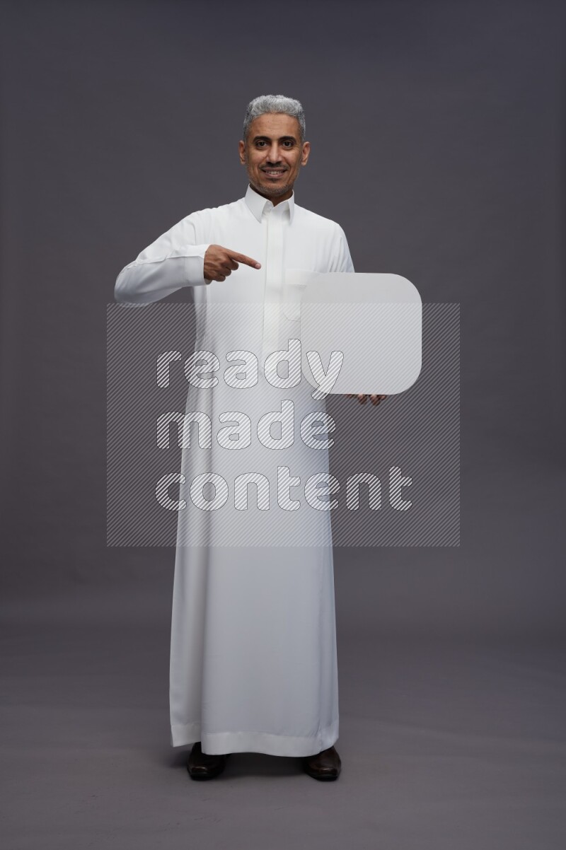 Saudi man wearing thob standing holding social media sign on gray background