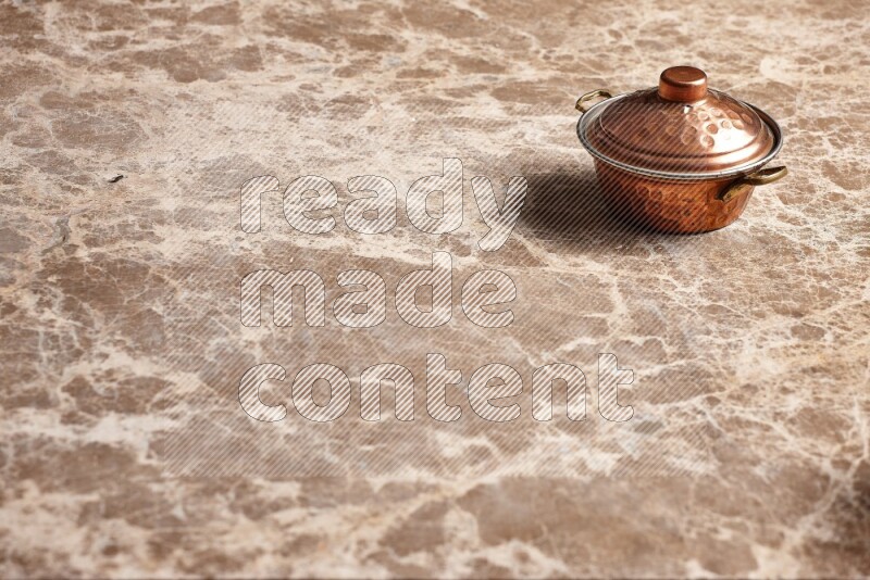 A small copper pot on beige marble background