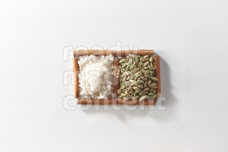 2 squares of cinnamon sticks full of cardamom and white salt on white flooring