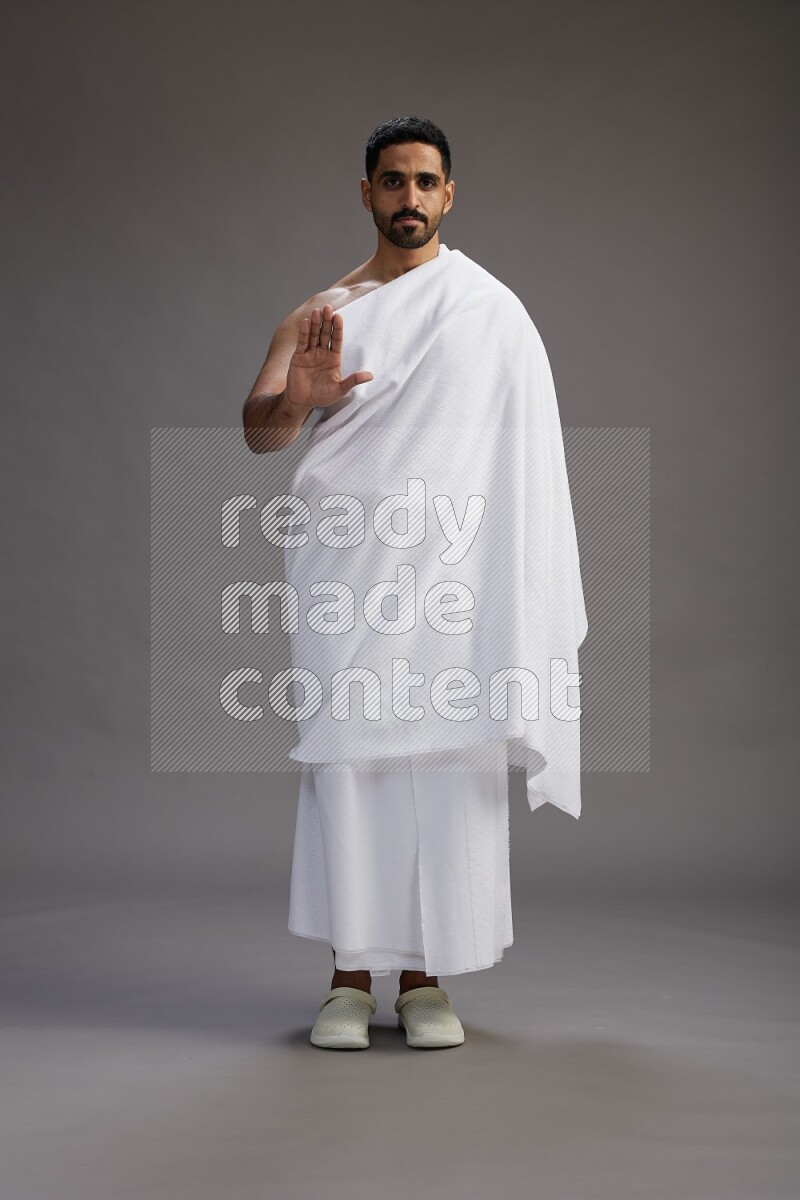 A man wearing Ehram Standing Interacting with the camera on gray background
