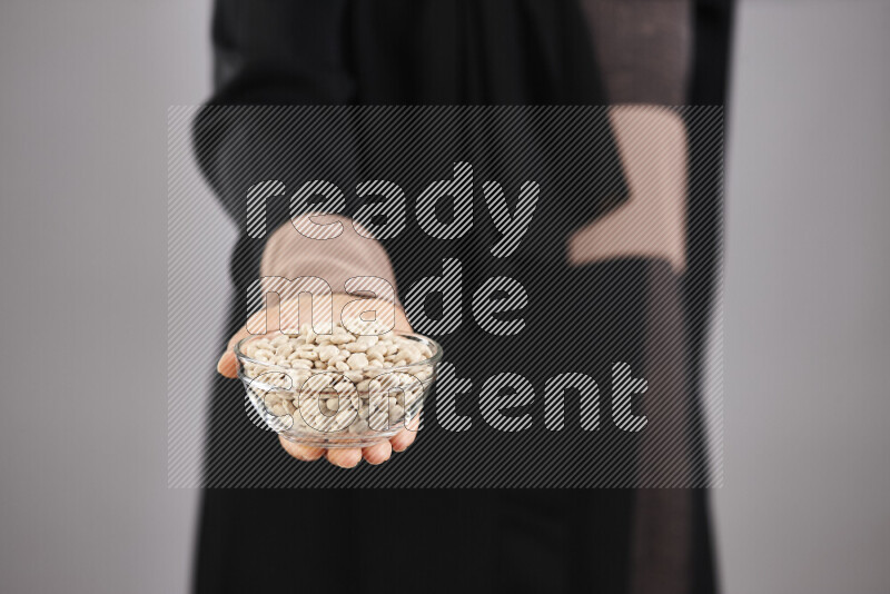 Woman in abaya holding different kinds of legumes in different positions