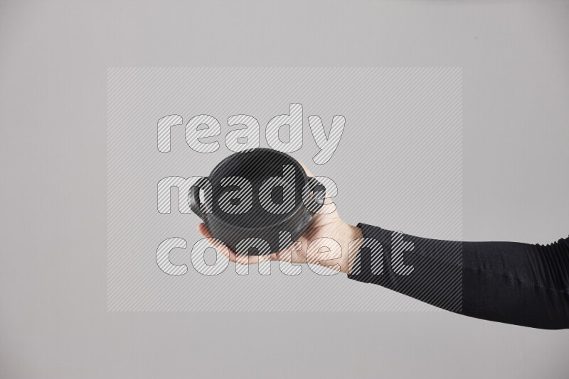 A woman in black abaya holding different pottery essentials in different positions