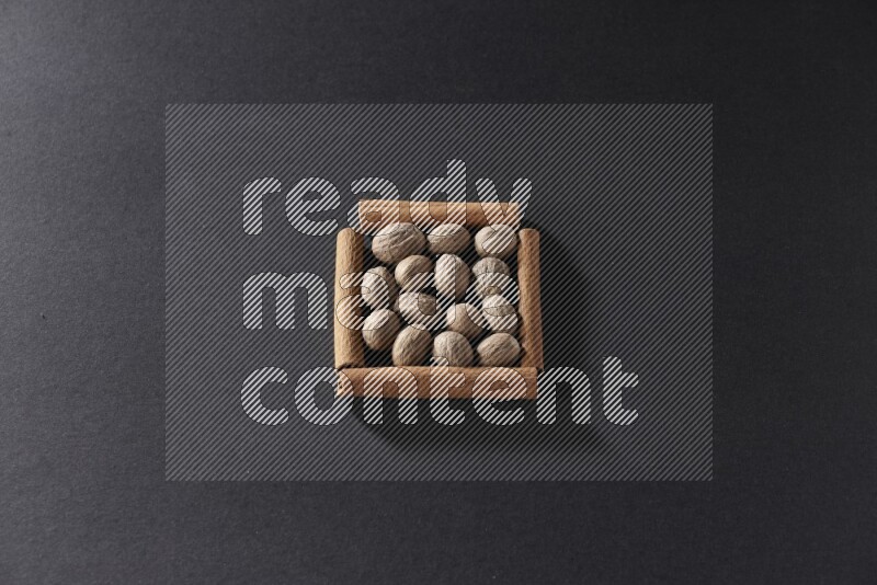 A single square of cinnamon sticks full of nutmeg on black flooring