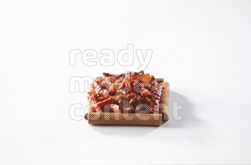 أربعة من أعواد القرفة مكونة شكل مربع بداخلها فلفل حار علي خلفية بيضاء