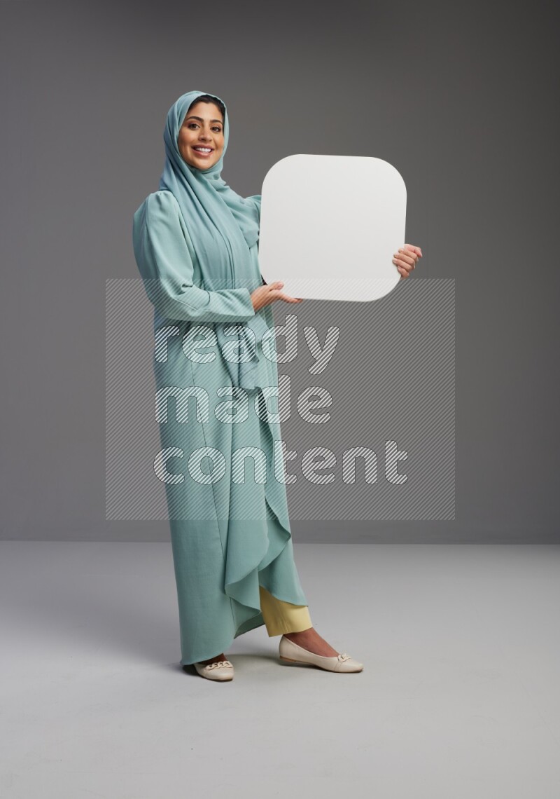 Saudi Woman wearing Abaya standing holding social media sign on Gray background