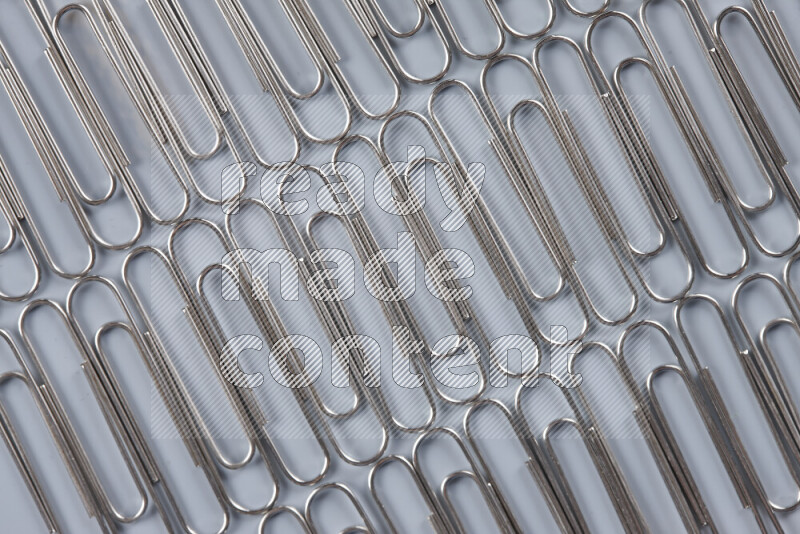Silver paper clips isolated on a grey background