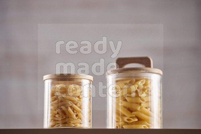Raw pasta in glass jars on beige background