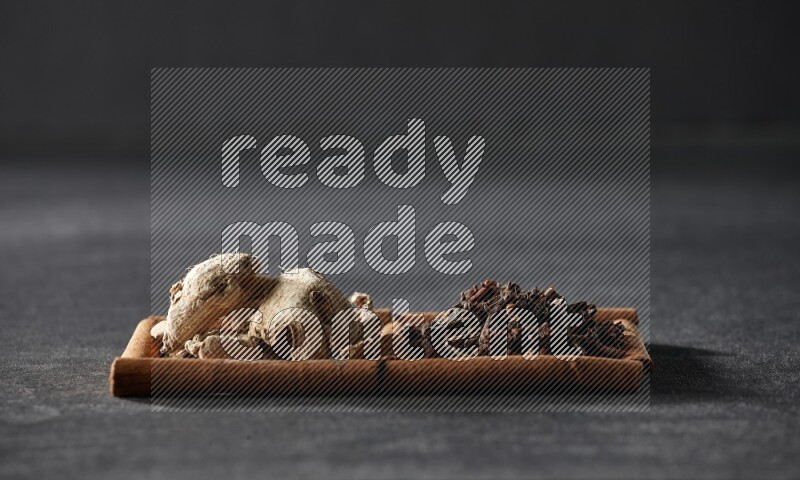 2 squares of cinnamon sticks full of cloves and dried ginger on black flooring