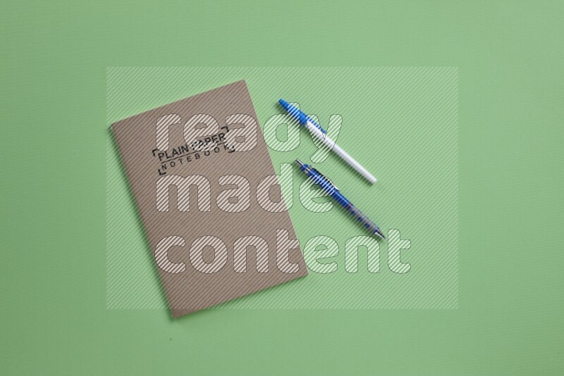 A notebook with different school supplies on green background