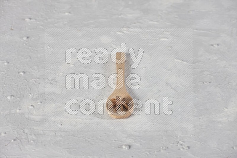 Star Anise in a wooden spoon on white flooring