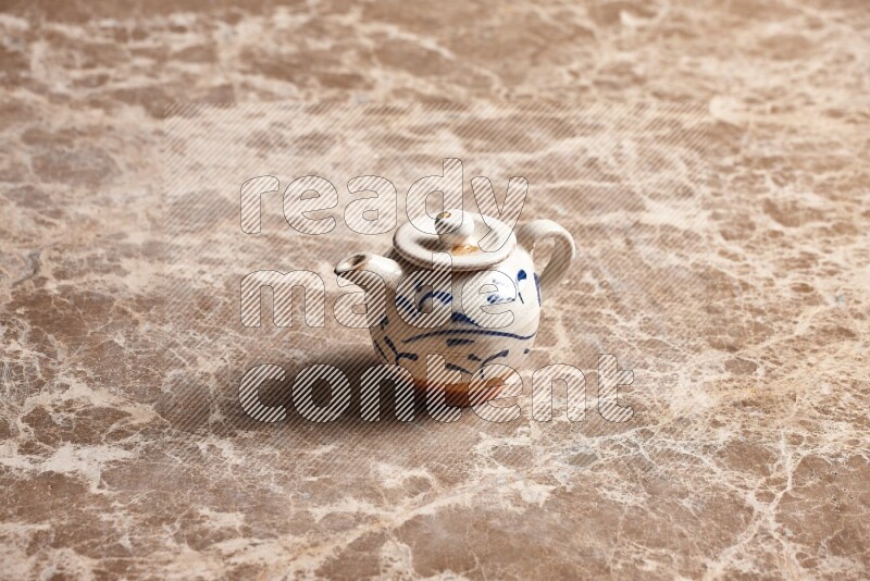 A pottery teapot on beige marble background