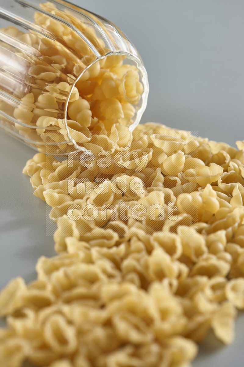 Flipped jar full of raw pasta on light blue background