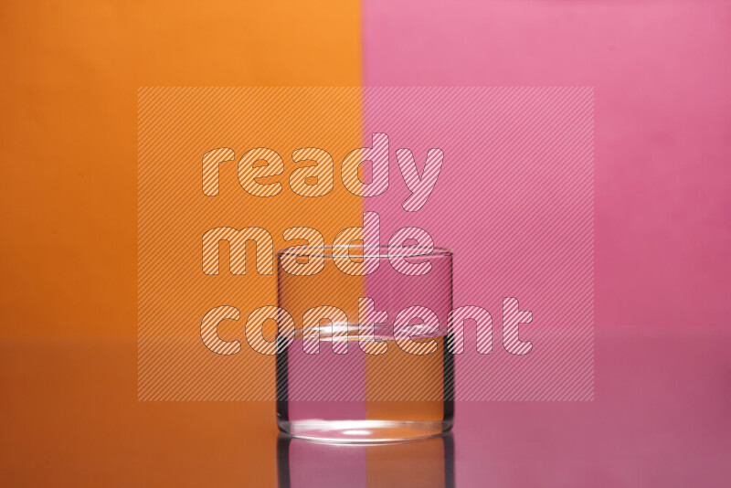 The image features a clear glassware filled with water, set against orange and pink background