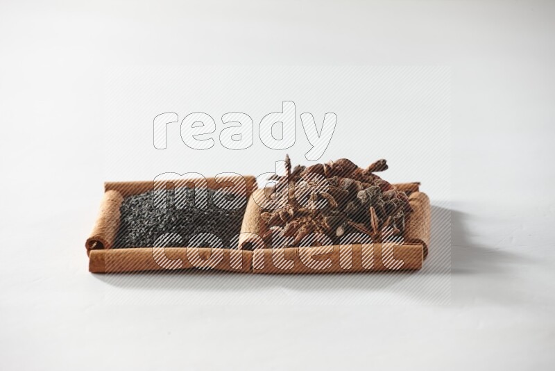 مربعان من أعواد القرفة ممتلئان بحبة البركة السوداء واليانسون النجمي علي خلفية بيضاء