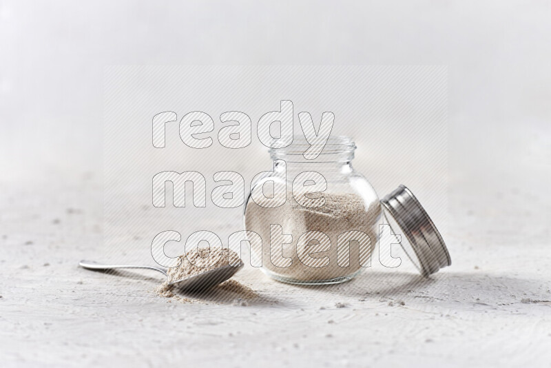 A glass jar full of onion powder on white background