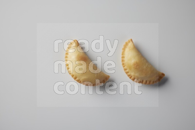 Two fried sambosa from a top angle on a white background