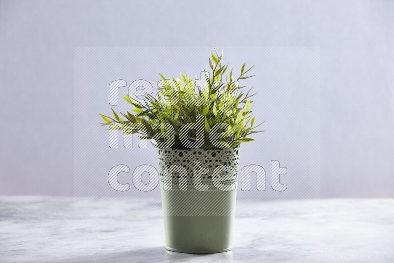 Artificial plant in green decorative pot on grey marble background