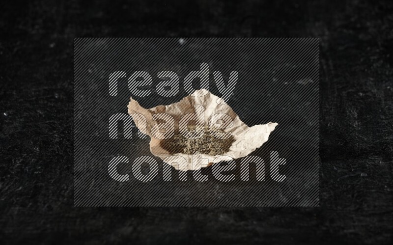 بودرة الهيل في قطعة من الورق على خلفية سوداء