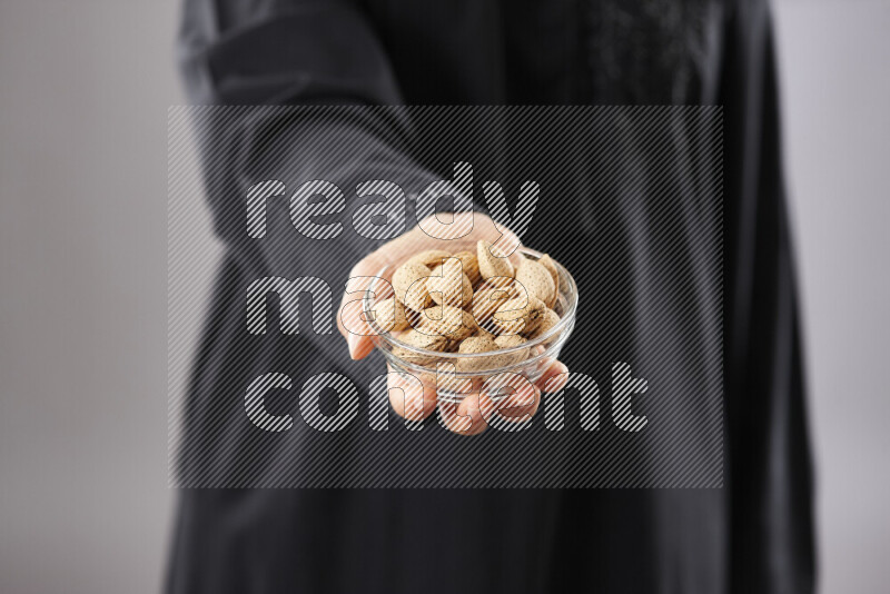 Woman in abaya holding different kinds of nuts in different positions