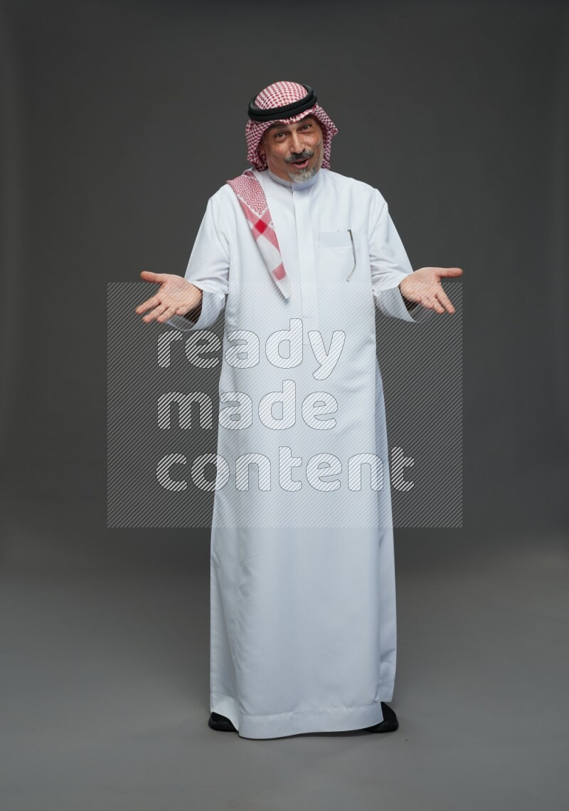 Saudi man with shomag Standing Interacting with the camera on gray background