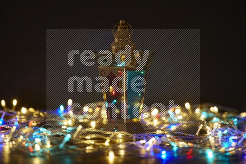 A traditional ramadan lantern surrounded by glowing fairy lights in a dark setup