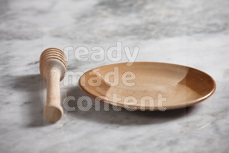 Multicolored pottery plate with wooden honey dipper on the side on grey marble background