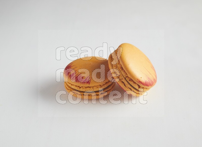 45º Shot of two orange Exotic macarons on white background