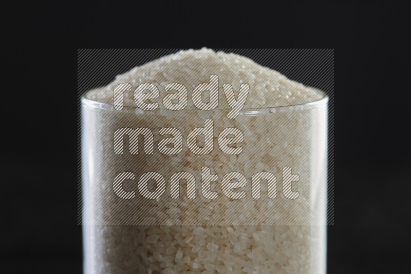 White rice in a glass jar on black background