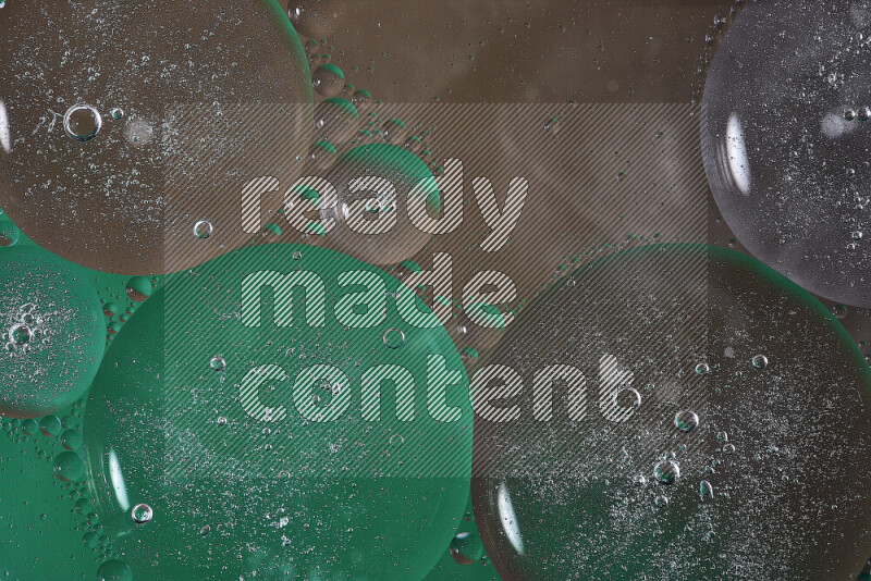 Close-ups of abstract oil bubbles on water surface in shades of green and brown