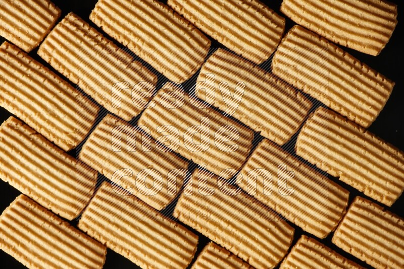 Golden biscuits filling the frame on black background
