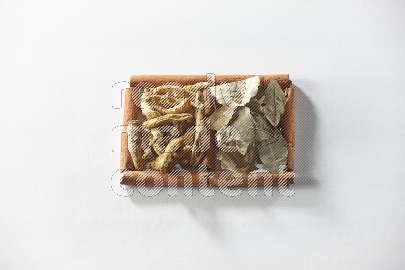 2 squares of cinnamon sticks full of turmeric fingers and bay laurel leaves on white flooring