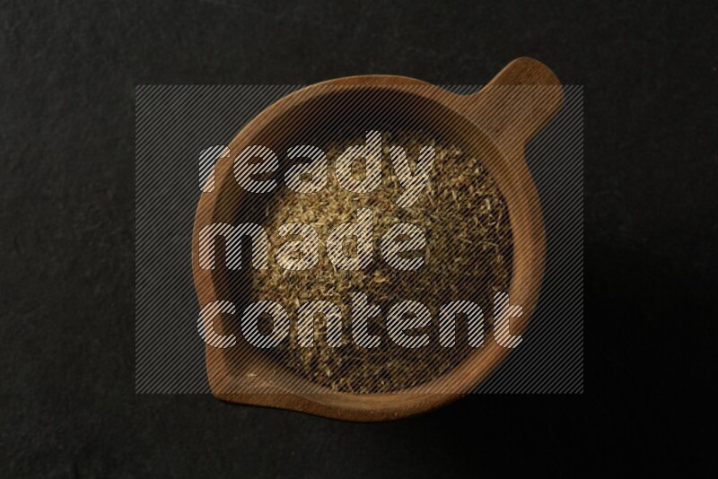 wooden round sauce bowl filled with herbs on grey textured countertop