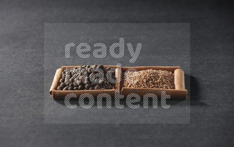 مربعان من أعواد القرفة ممتلئان بحبوب الخردل وحبوب بهار الفلفل الحلو علي خلفية سوداء