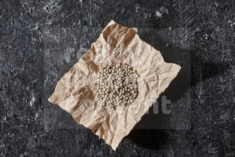 White pepper beads in a crumpled piece of on textured black flooring