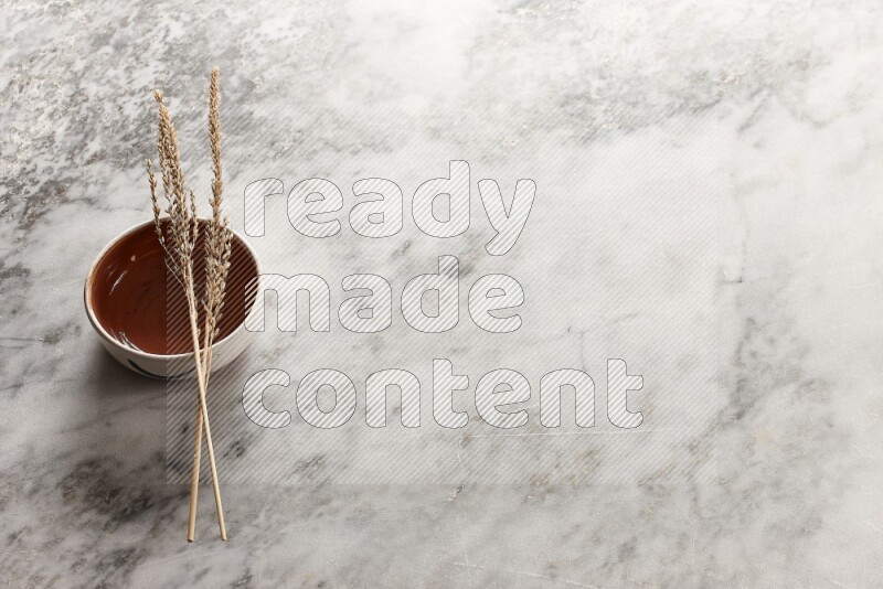 Wheat stalks on brown pottery bowl on grey marble background