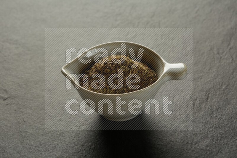 white ceramic round sauce bowl filled with herbs on grey textured countertop
