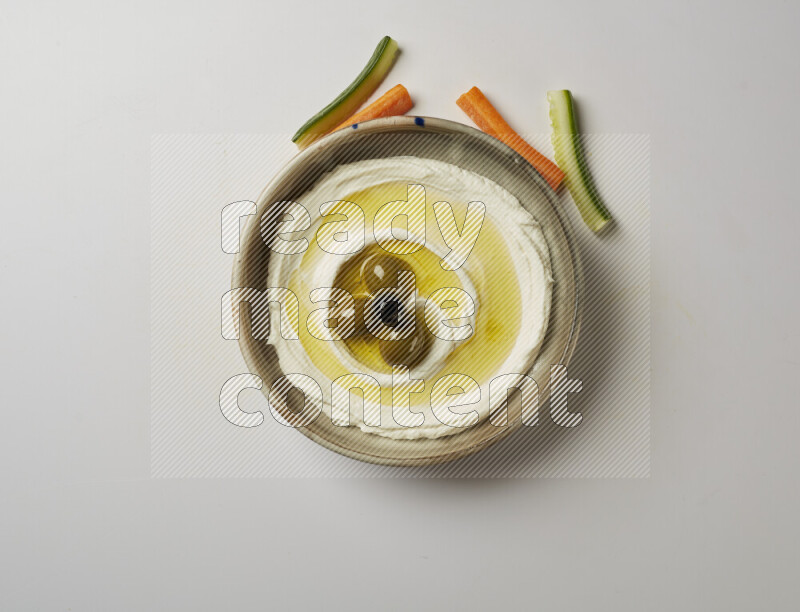 Lebnah garnished with whole olives in a grey pottery plate on a white background