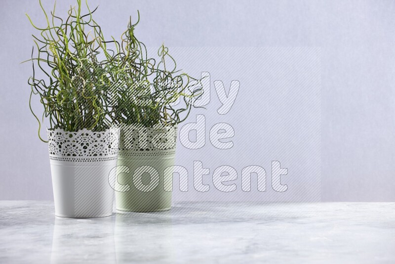 Two different artificial plants in white and green decorative pots on grey marble background