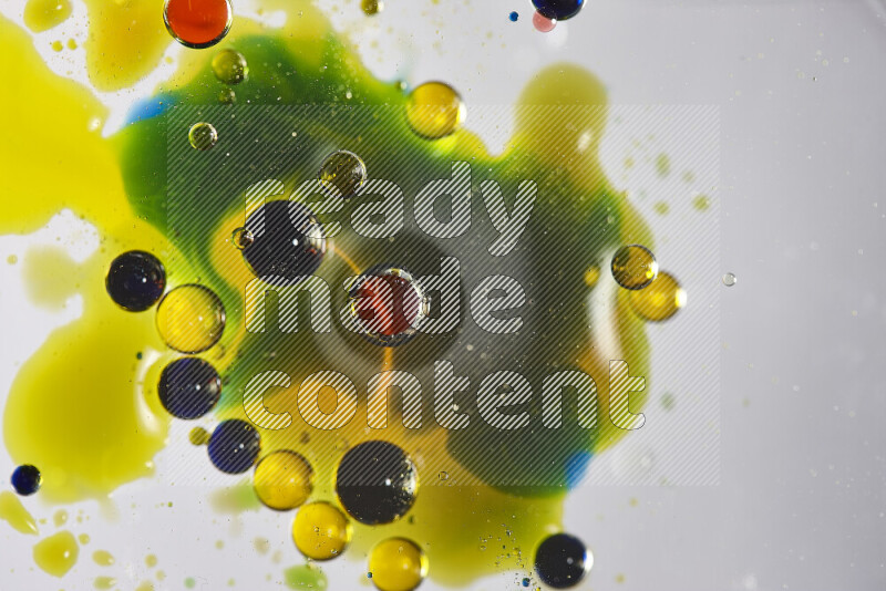 Close-ups of abstract red, blue, yellow and green watercolor drops on oil Surface on white background