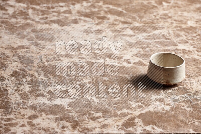 A beige pottery bowl on beige marble background